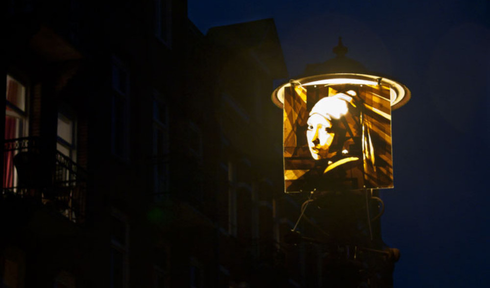 Artwork made of packing tape hung up on a street lamp in Amsterdam depicting the girl with the pearlearring, by Max Zorn. Kunst mit Klebeband, art du ruban