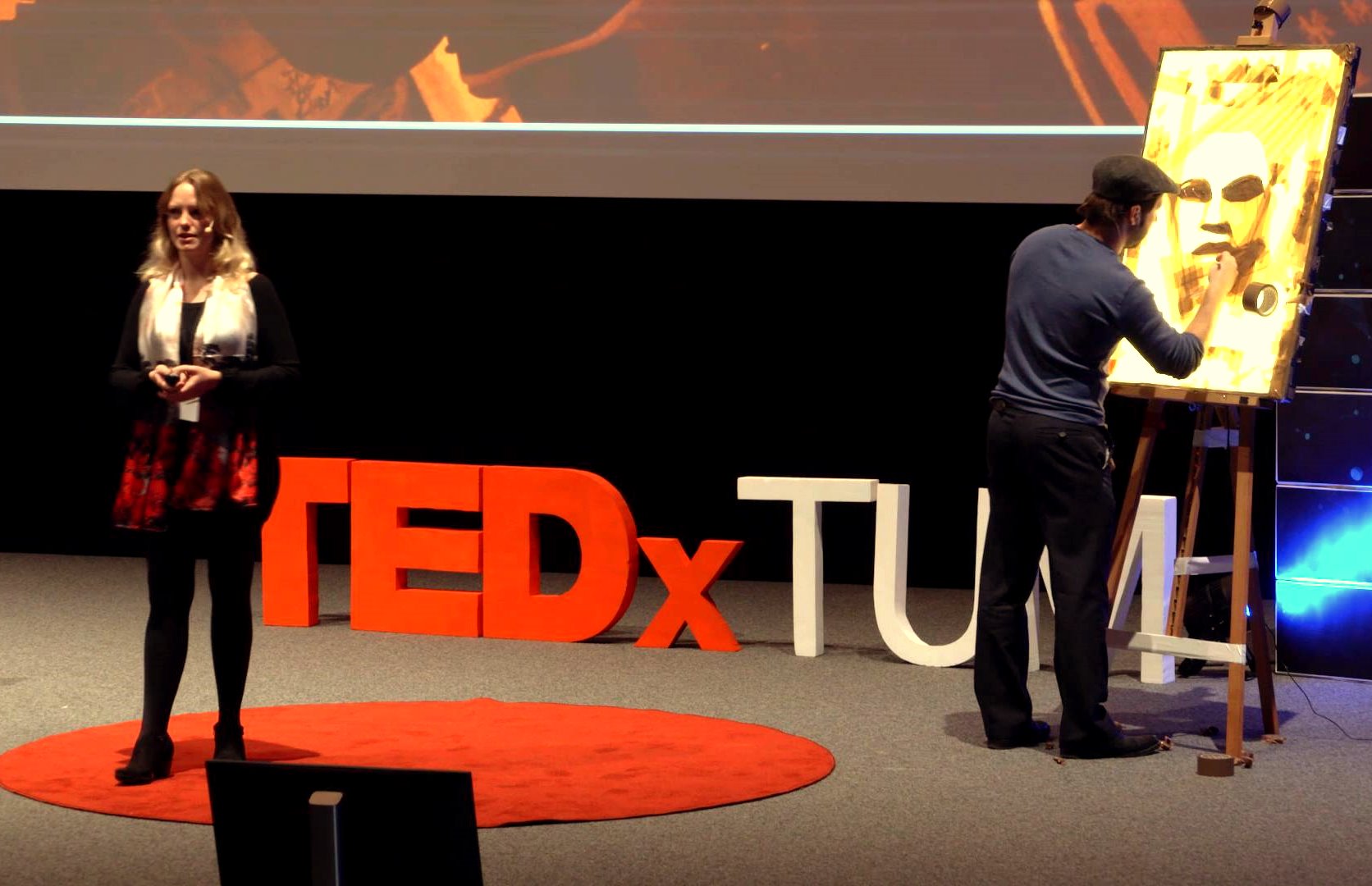Max Zorn demonstrating tape art technique during his TED Talk, layering packing tape on illuminated acrylic.