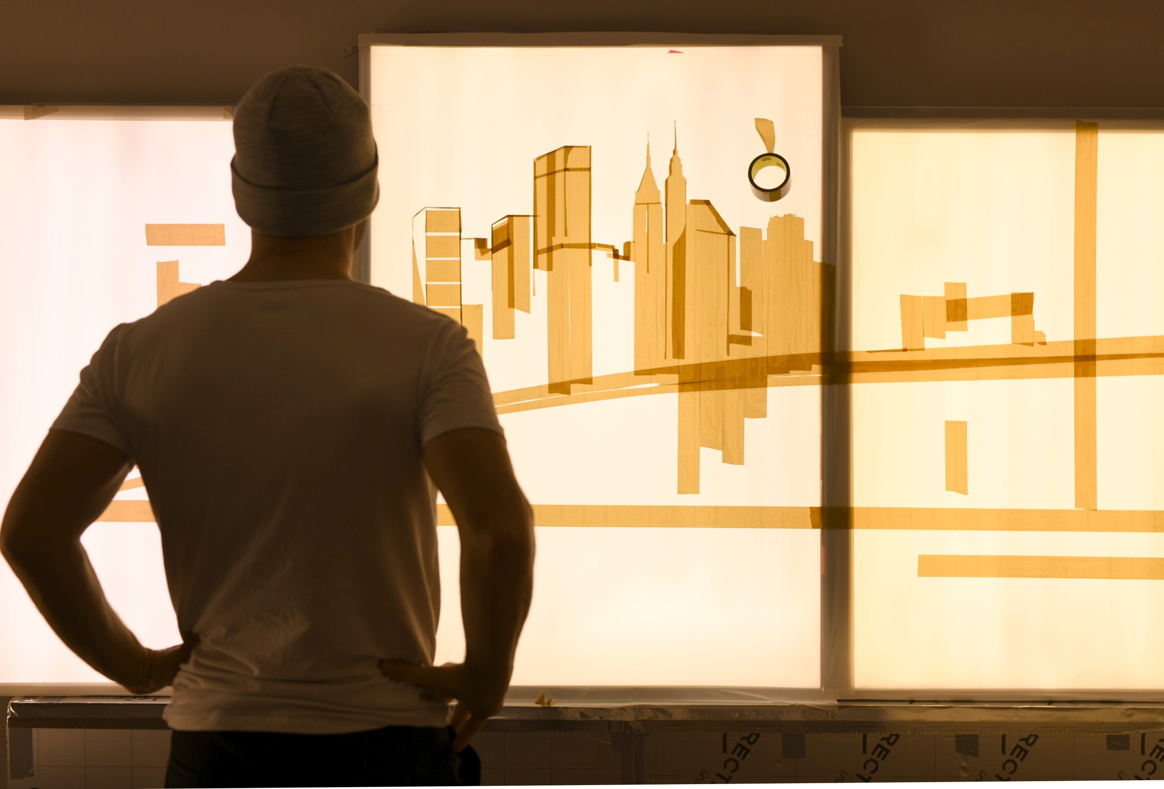 Max Zorn studies the early skyline of Dream, with broad strips of packing tape defining the buildings and waterfront.