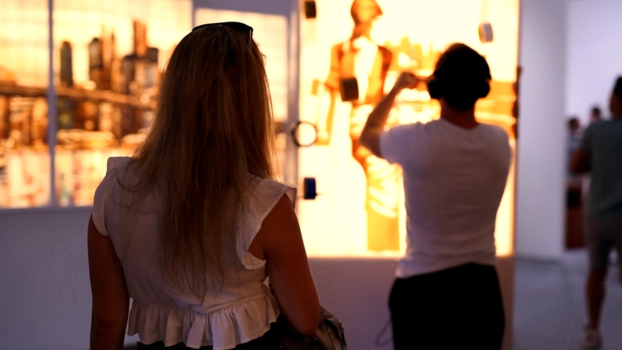 A visitor watches Max Zorn making an illuminated tape artwork at an international art fair.